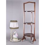 A mahogany three tier folding cake stand, together with a Capo di Monte figural table lamp