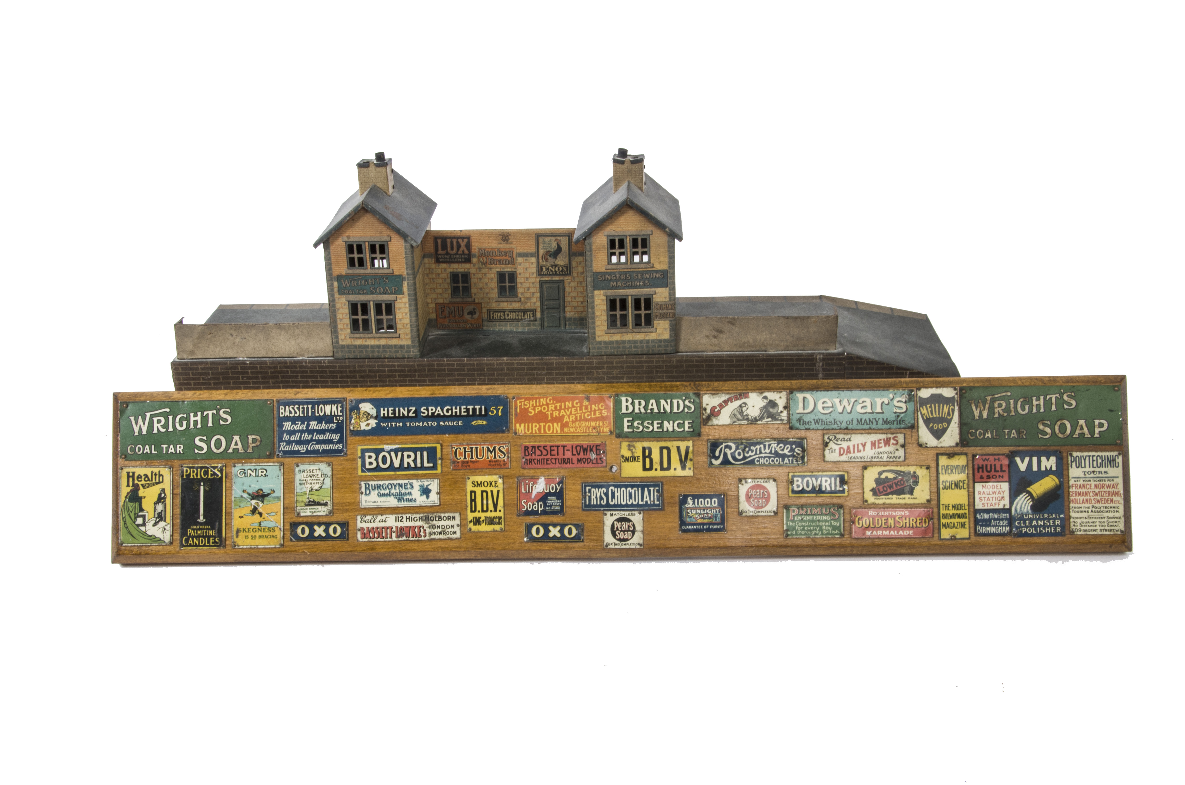 A Bing O Gauge Wayside Station and Bassett-Lowke Enamel Signs Display Board, the station with twin