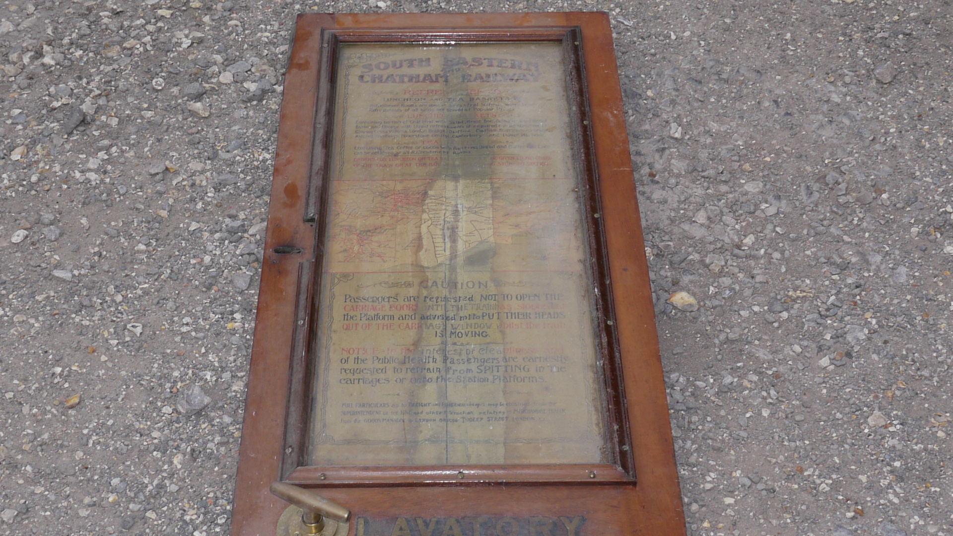 An Edwardian Railway Carriage Lavatory Door, teak door with upper glazed panel inset with poster