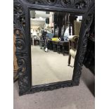 A carved oak wall mirror with bevelled edge glass