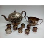 A silver plated teapot, sugar bowl and napkin ring