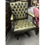 A green leather button back swivel chair.