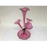 A reproduction cranberry epergne with four flutes.