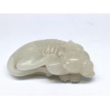 A small carved white jade model of a sleeping dog. Approx 5cm long.