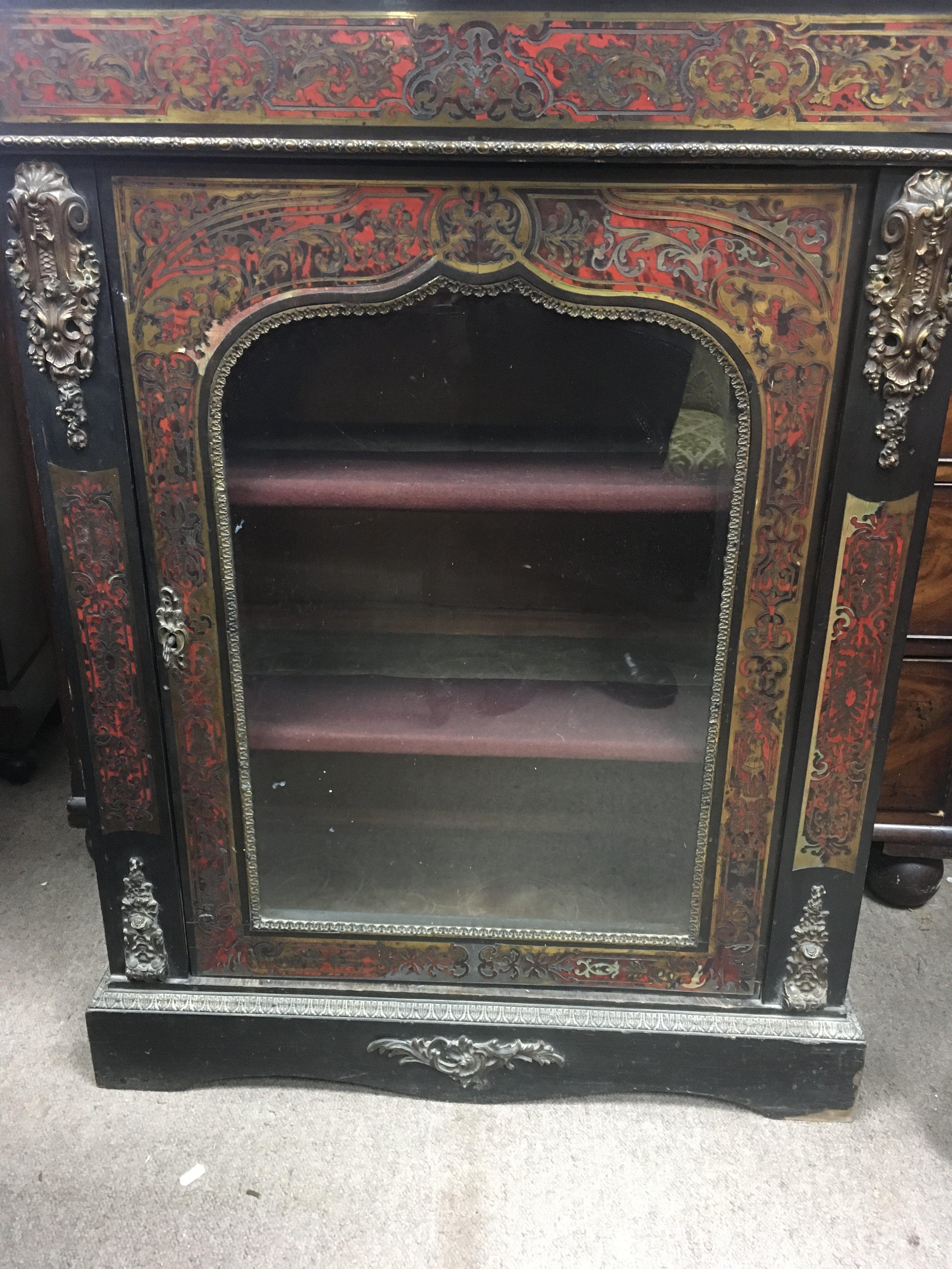 A boule pair cabinet with brass inlay and gilt metal mounts the single door enclosing selfs on a