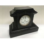 An 8 day black slate mantle clock with floral swag decoration.