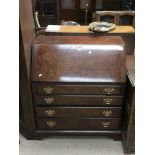 A reproduction mahogany bureau with brass handles.