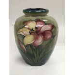 A Moorcroft vase depicting lilies on a green groun