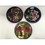 Three Moorcroft dishes decorated with flowers, one