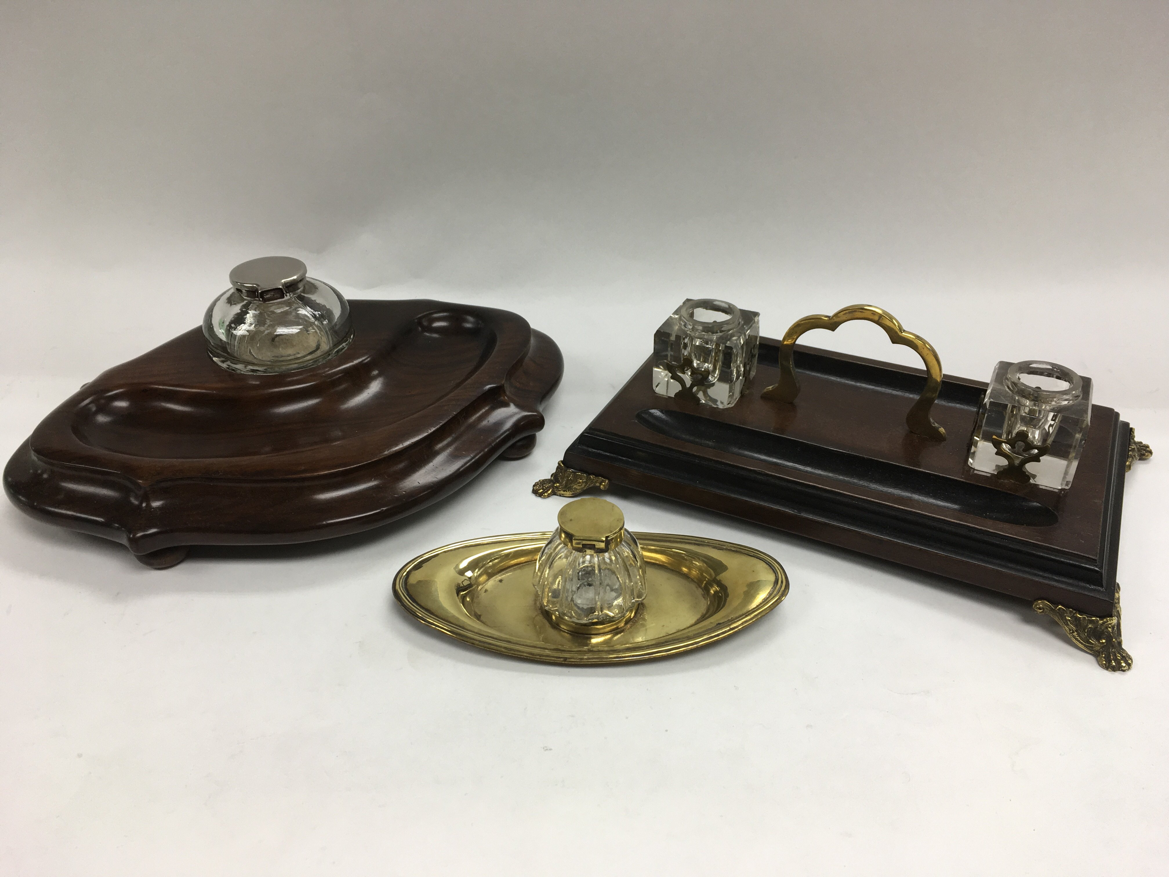 Three inkwells comprising two on wooden bases and