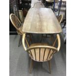 An Ercol lightwood dining table and four chairs in