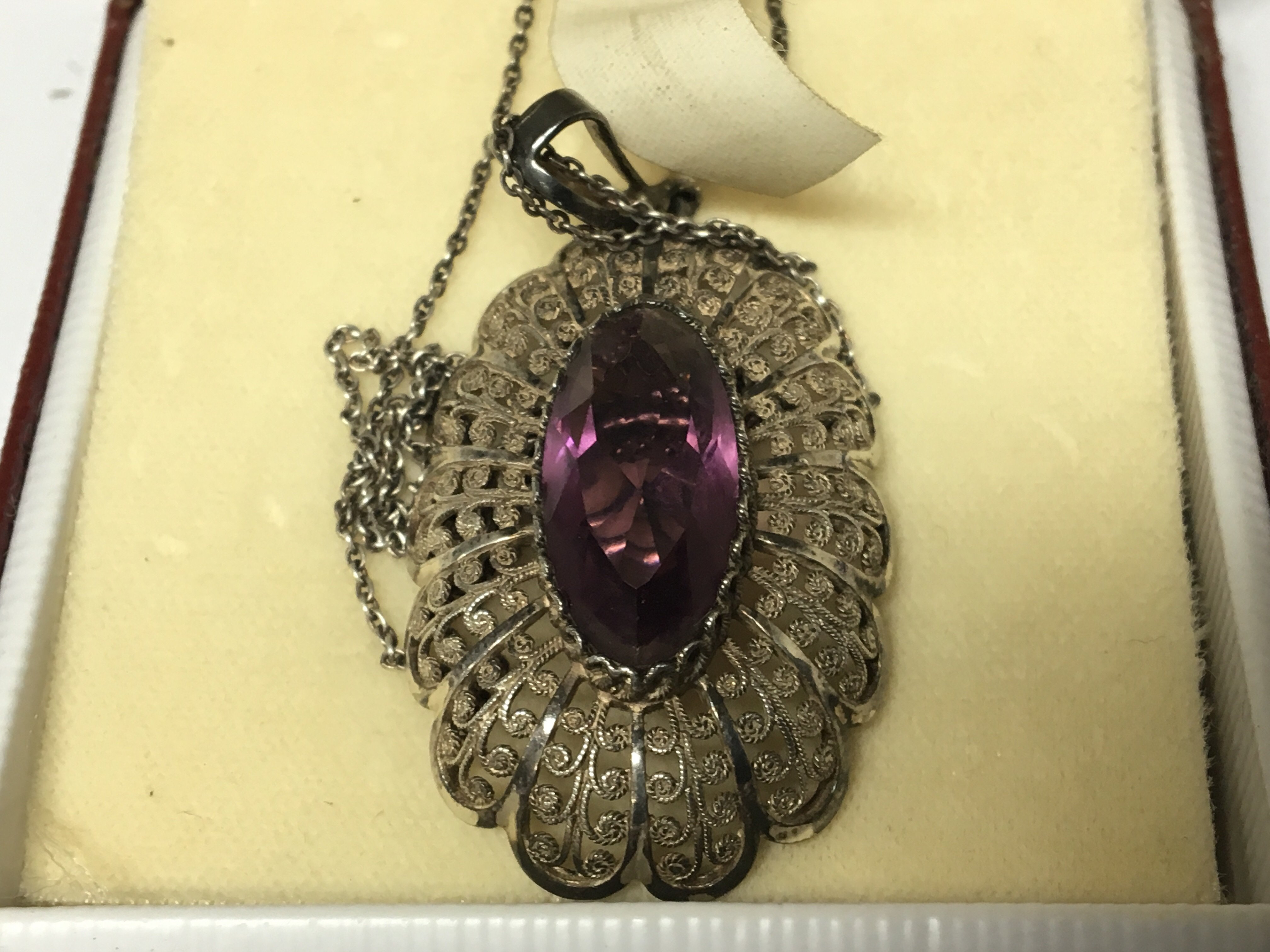 A Silver fillagree brooch set with an amethyst col