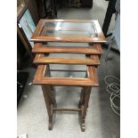 A nest of Edwardian glass topped occasional tables