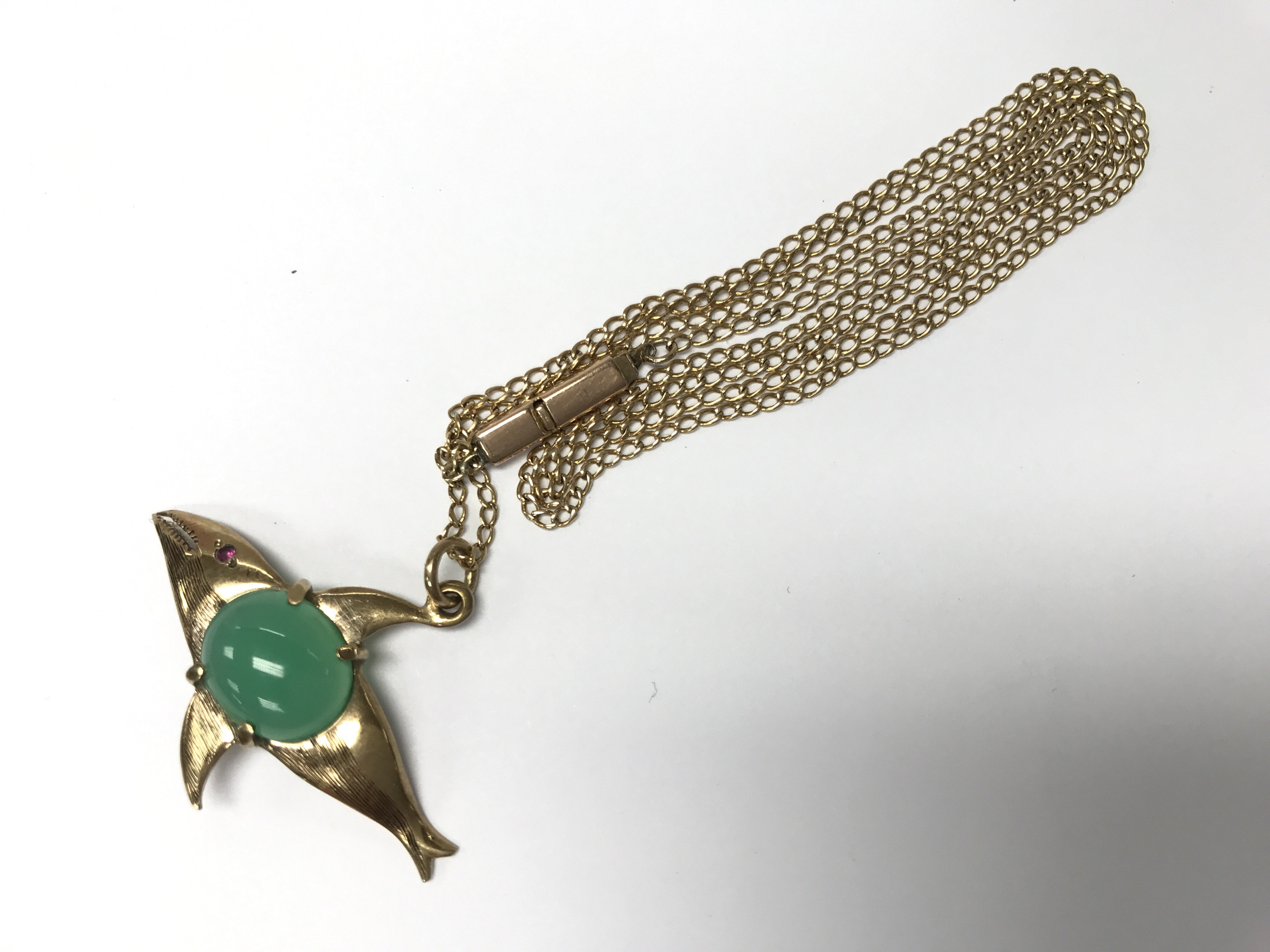 A 9ct gold whale pendant with green coloured stone