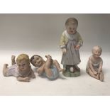 A collection of 4 piano dolls depicting babies and