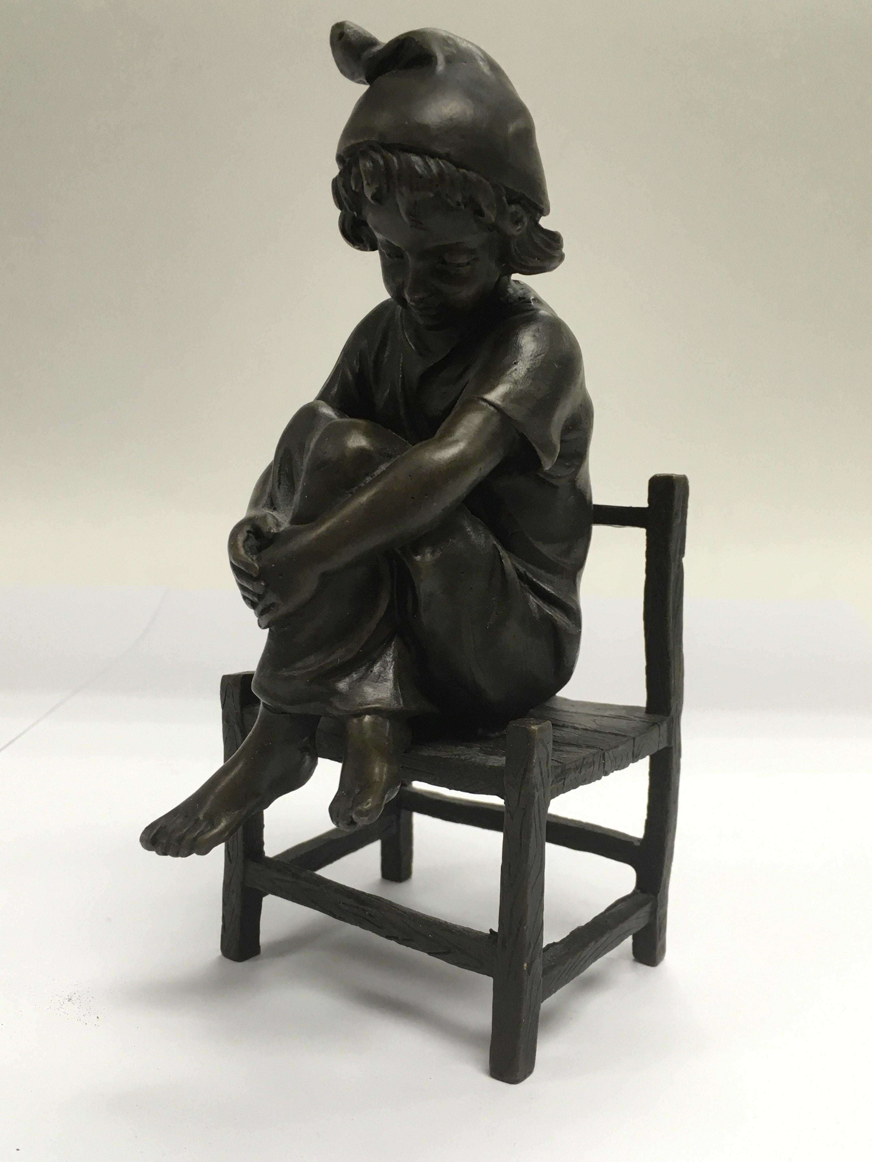 A small French bronze of a child seated on a chair