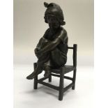 A small French bronze of a child seated on a chair