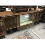 A retro cocktail sideboard fitted with two cupboard doors either side of central glazed sliding