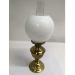 A brass oil lamp with glass globe shape shade