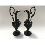 A Pair of late 19th Century bronze classical urns with shaped handles and raised decoration on red