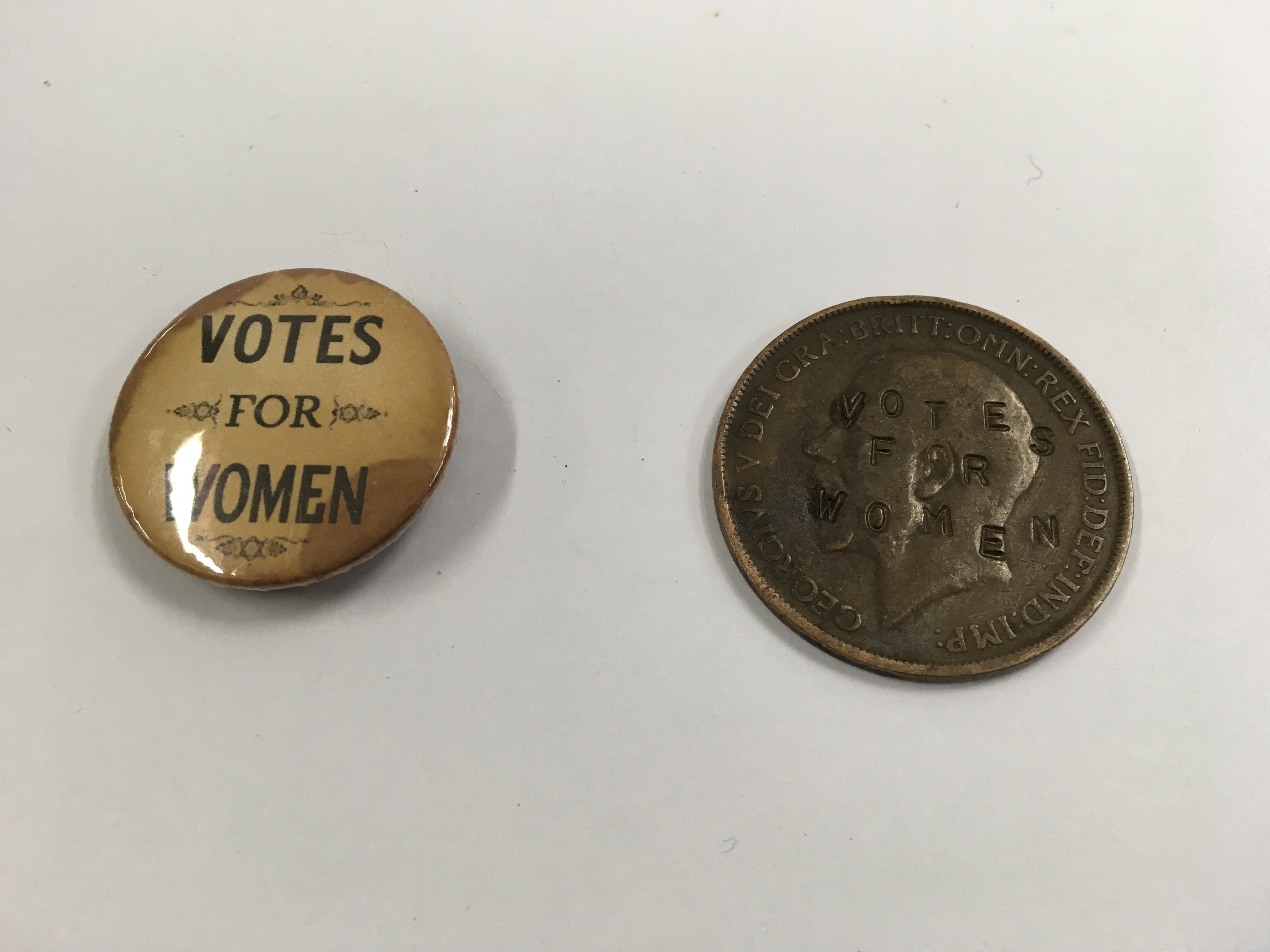 An unusual old penny stamped on the kings head with "votes for women" and a votes for women pin