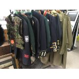 A collection of military jackets comprising two green greatcoats and others.