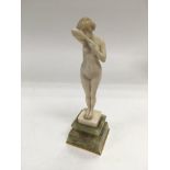 An ivory figure of a standing female nude, raised