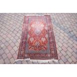 A Persian style rug with geometric and tomato fiel