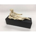 An ivory figure of a recumbent female nude raised