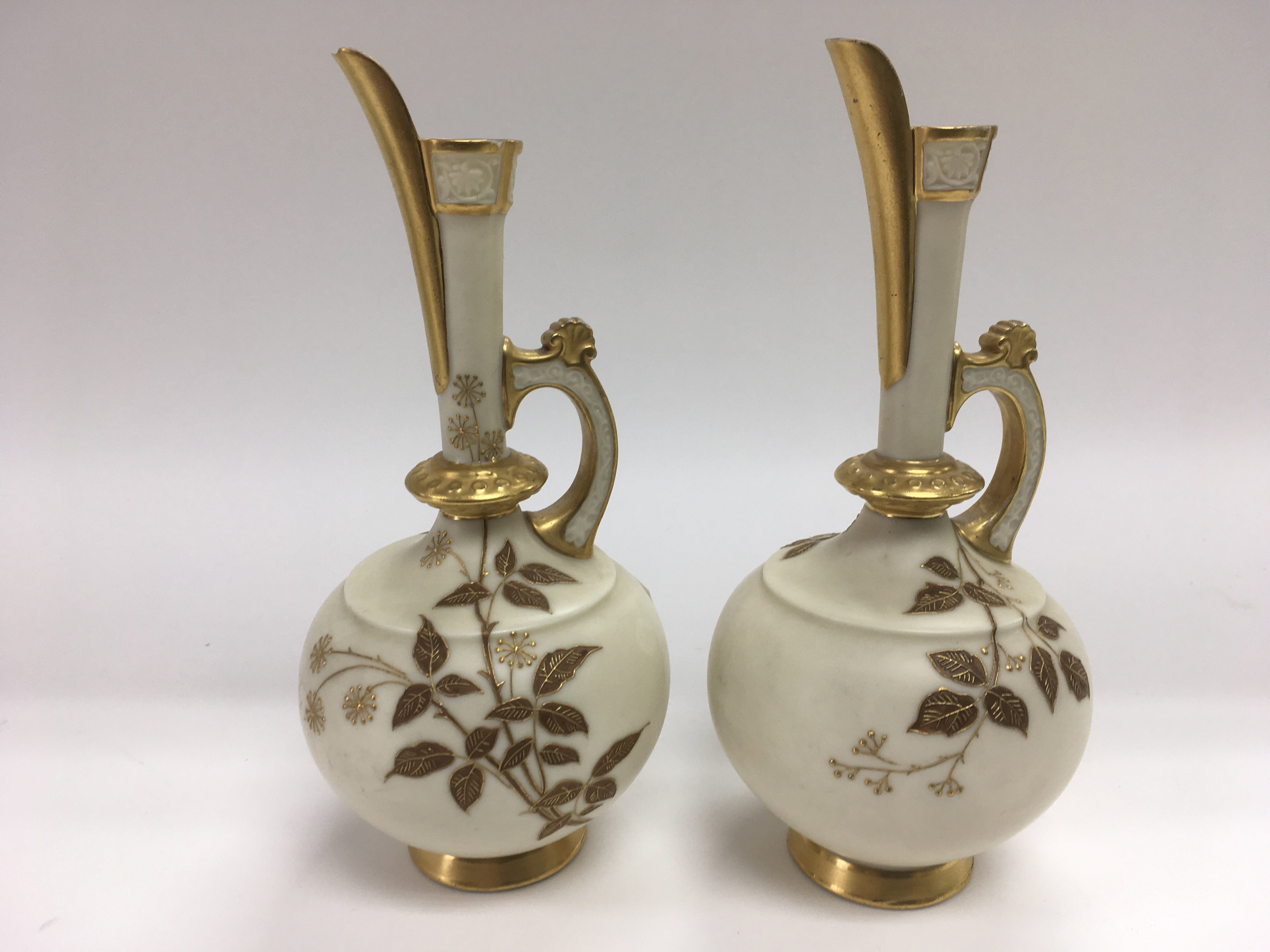 A pair of Royal Worcester jugs with giltwork decor