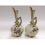 A pair of Royal Worcester jugs with giltwork decor