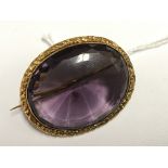 A large Amethyst type brooch set in yellow metal.