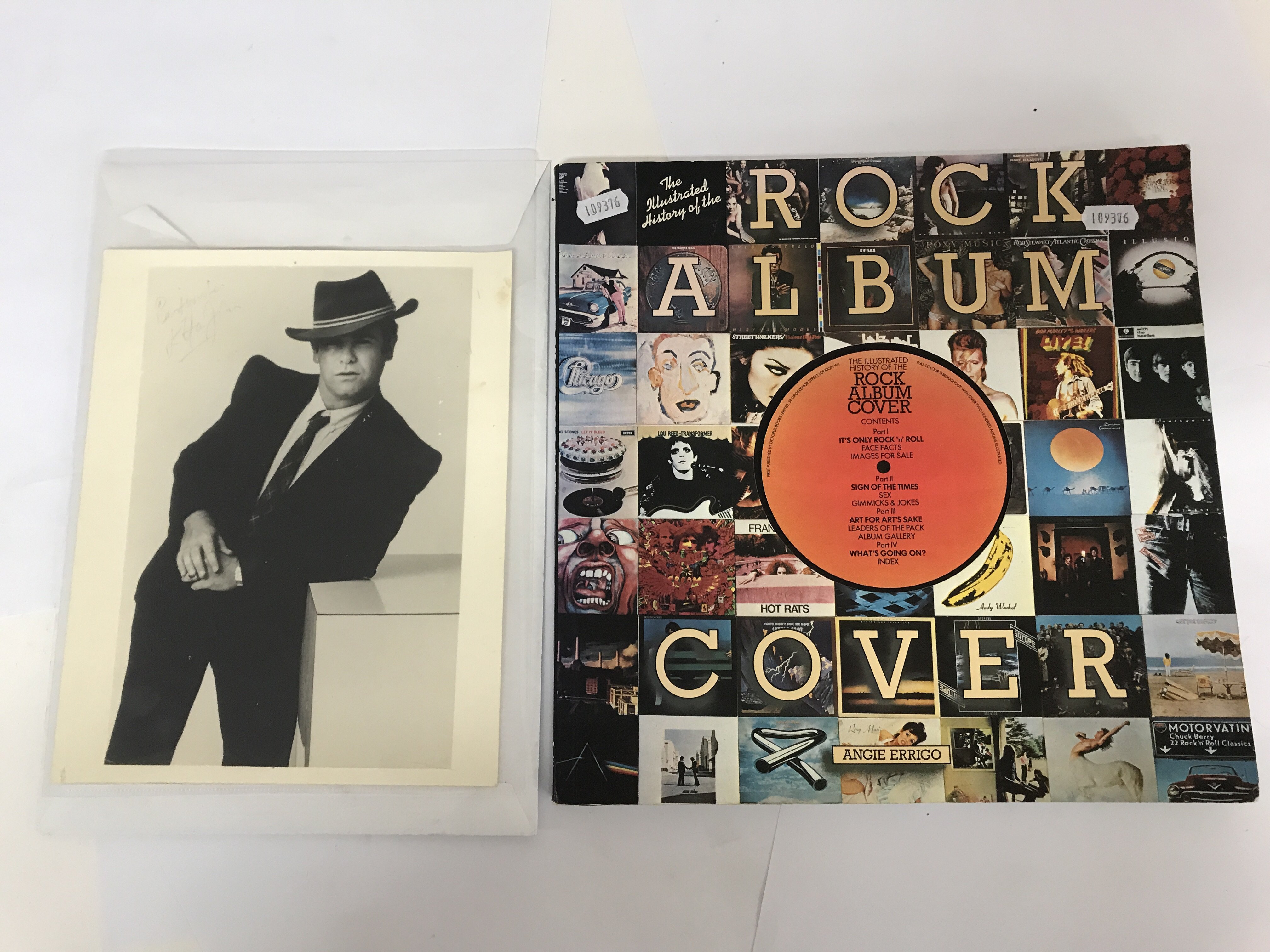 A signed 10"x8" black and white photograph of Elton John together with a book of 'Rock Album