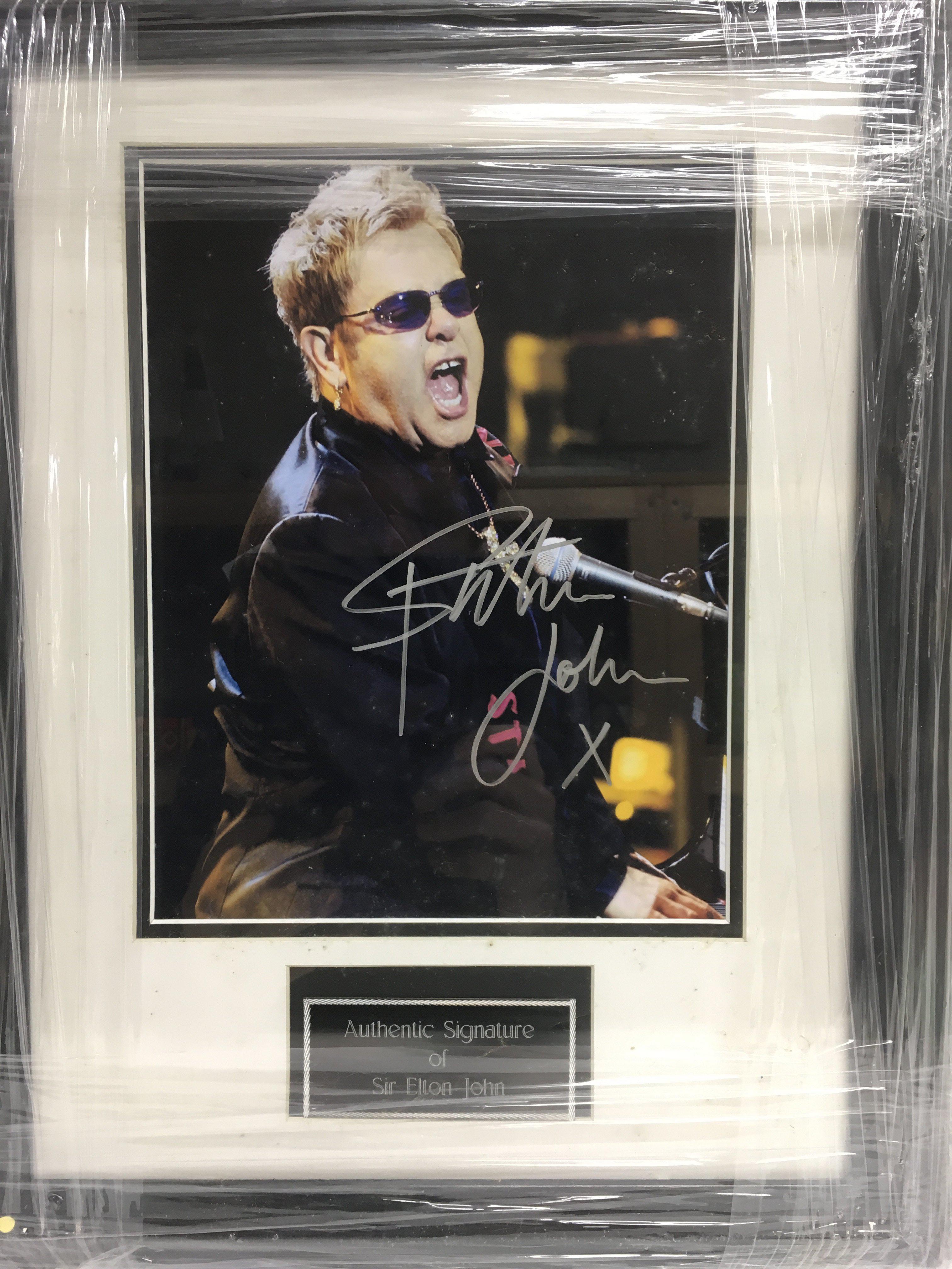 A framed and glazed photograph of Elton John with