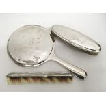 A three piece silver backed dressing table set com