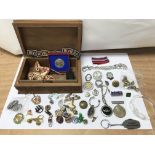 A carved box containing badges, buttons, medals et