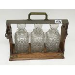 An Early 20th century oak tantalus with three cut glass square decanters