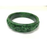 A dark green carved jade bangle.