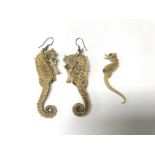 A pair of seahorses earrings along with one other.