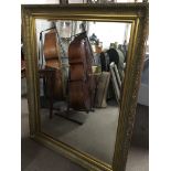 A large Gilt Framed modern mirror with a beveld edge . 145x115cm.