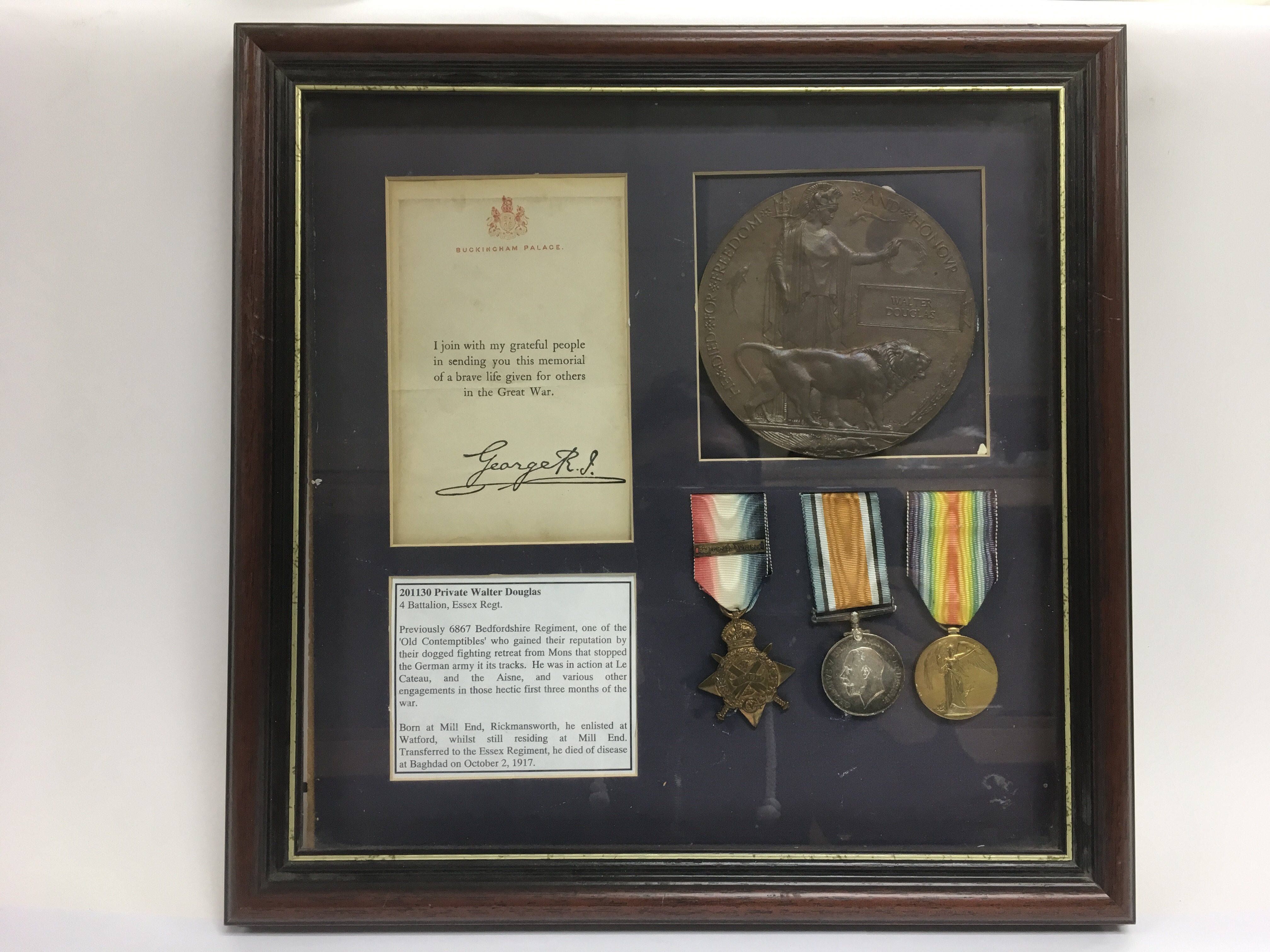 A framed and glazed montage of WW1 medals and a de