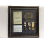 A framed and glazed montage of WW1 medals and a de