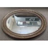 A large oval mirror with decorative wood frame.App