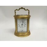 A French engraved gilt brass oval carriage clock with push button repeat and alarm the dial with