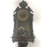 A 19th century continental carved oak Black Forest type wall clock with a visible pendulum and