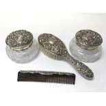 A pair of silver topped tidy jars, a brush and comb.