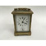 A French brass case carriage clock the white dial with Roman numerals and visible escapement