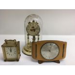 A brass anniversary clock under a glass dome, an 8 day carriage clock and a mantel clock