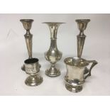 A collection of silver comprising a small silver mug match holder pair of candle sticks and a vase.