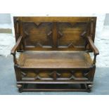 A carved oak monk's bench with shaped fluted arms,